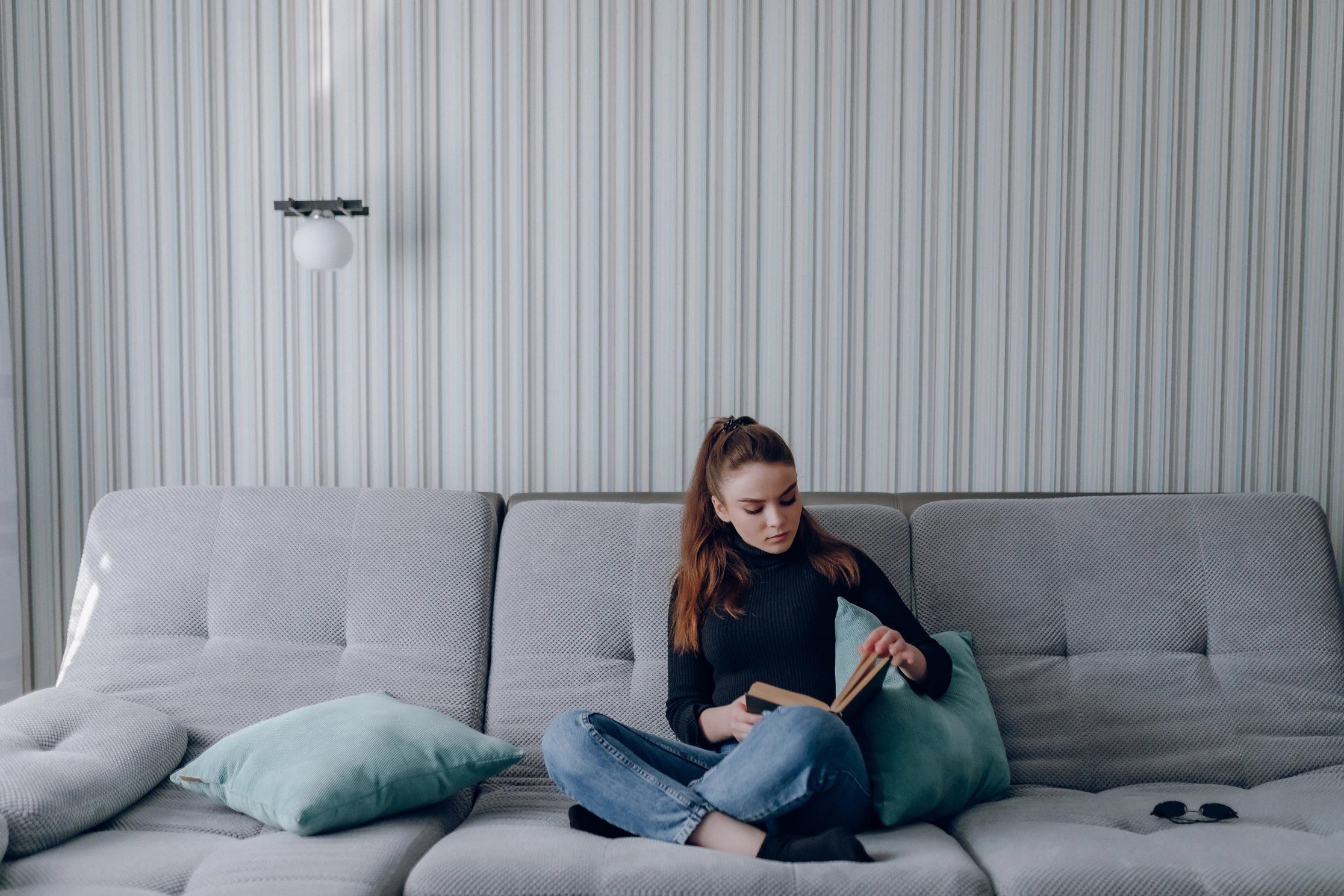 Kobieta szukająca odpowiedzi w książce siedząc na kanapie.